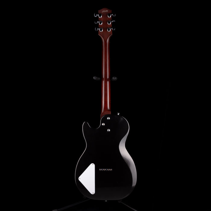 Black electric guitar with a white pickguard on a black background