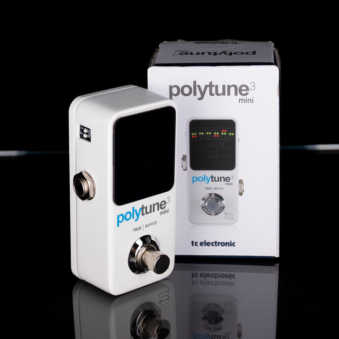 PolyTune mini guitar tuner with packaging on a reflective surface