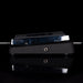 Guitar effects pedal with a dark finish on a reflective surface
