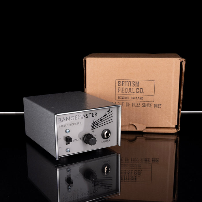 Rangemaster guitar pedal with a cardboard box labeled 'British Pedal Co.' on a reflective surface.
