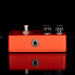 Orange guitar effects pedal with knobs and jacks on a black background