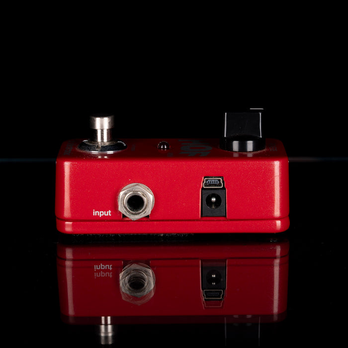 Red guitar effects pedal with input and output jacks on a black background
