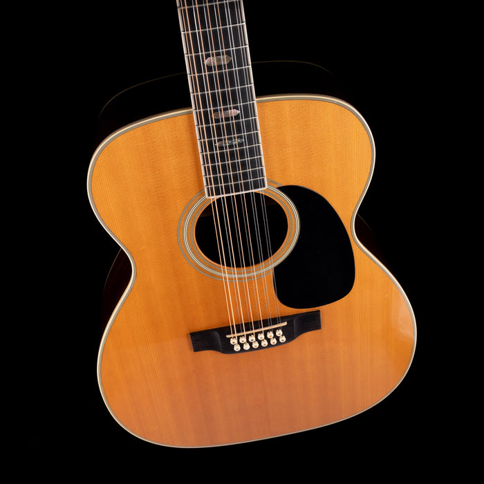 Acoustic guitar with a wooden body and black pickguard on a white background