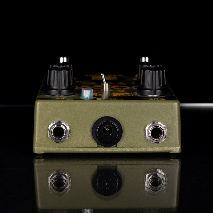 Guitar effects pedal with knobs and jacks on a reflective surface