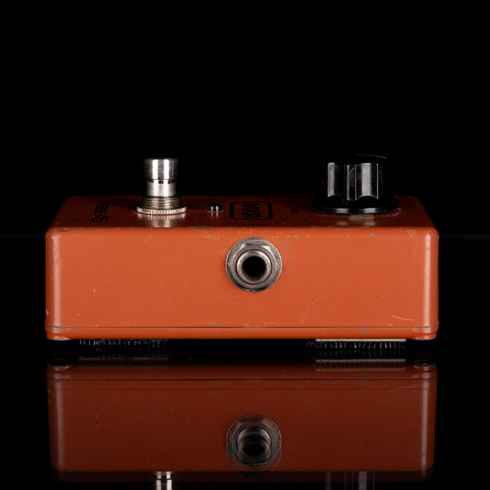 Brown guitar effects pedal with knobs on a black background