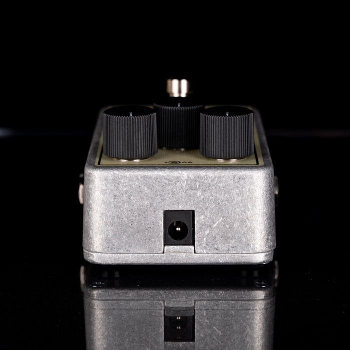 Guitar effects pedal with knobs and a jack on a black background