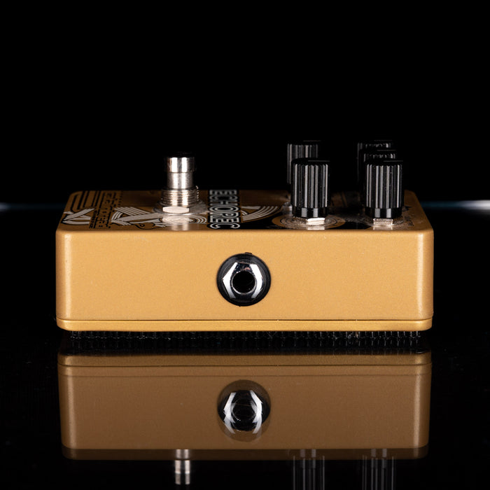 Gold guitar effects pedal with knobs on a black background