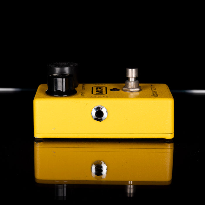 Yellow guitar effects pedal with black knobs on a black background