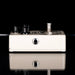 White guitar effects pedal with black knobs on a reflective surface
