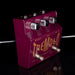Purple guitar effects pedal with 'Tremolo' branding on a reflective surface.
