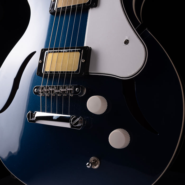 Close-up of a blue electric guitar with a black pickguard