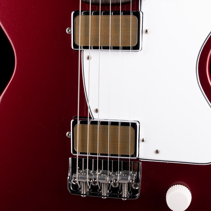 Close-up of a red electric guitar with white pickguard