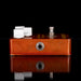 Wooden guitar effects pedal with metal and plastic components on a black background