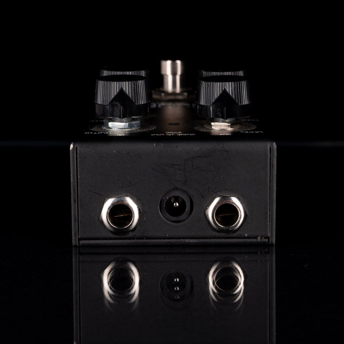 Black electronic device with metallic knobs and connectors on a black background