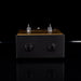 Black and wooden effect pedal on a reflective surface with a black background