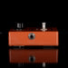 Brown guitar effects pedal with knobs on a black background