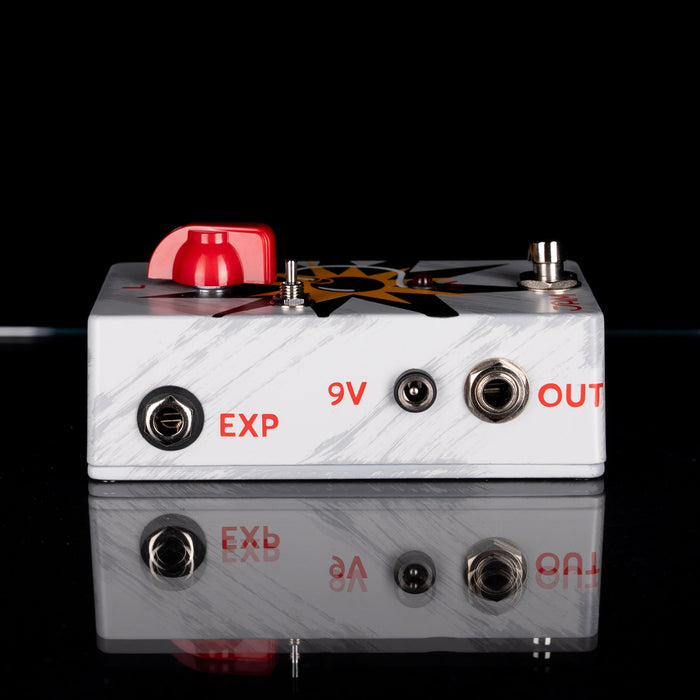 Guitar effects pedal with a red knob and labeled ports on a black background