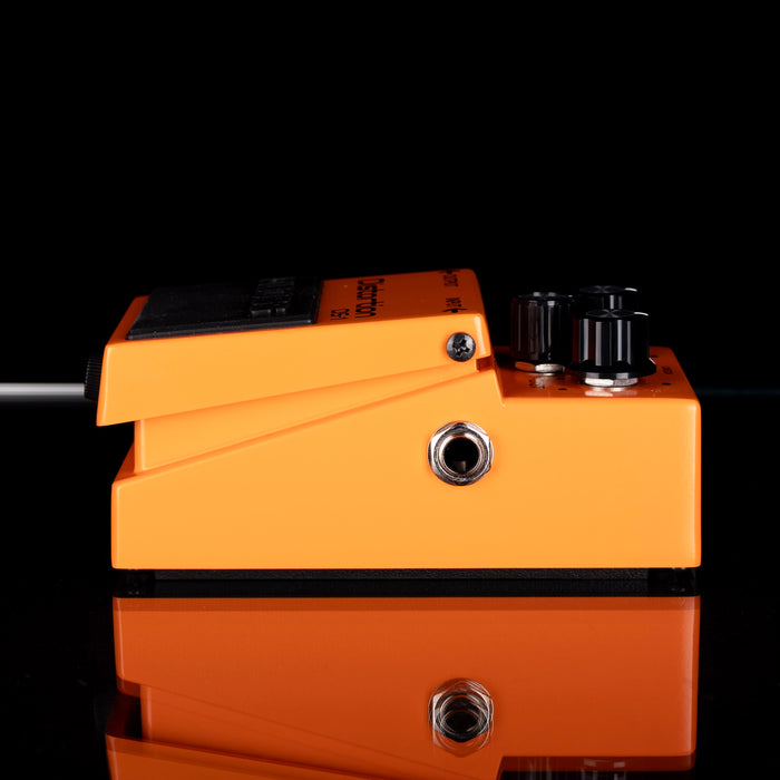 Orange guitar effects pedal with knobs and jacks on a black background