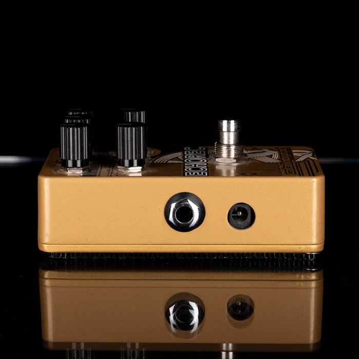 Guitar effects pedal with knobs and jacks on a reflective surface