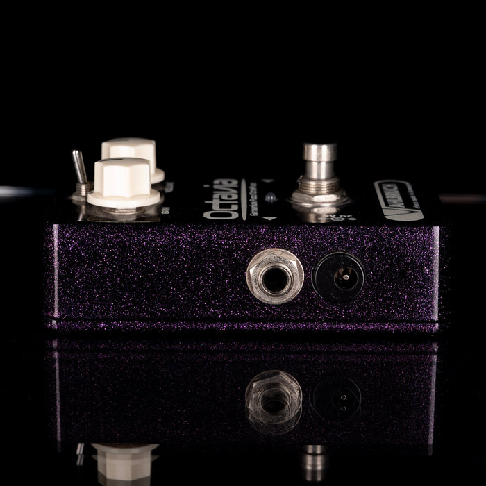 Close-up of a guitar effects pedal with visible branding on a black background