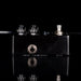 Black guitar effects pedal with metallic knobs on a black background