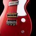 Close-up of a red electric guitar with a black pickguard on a dark background