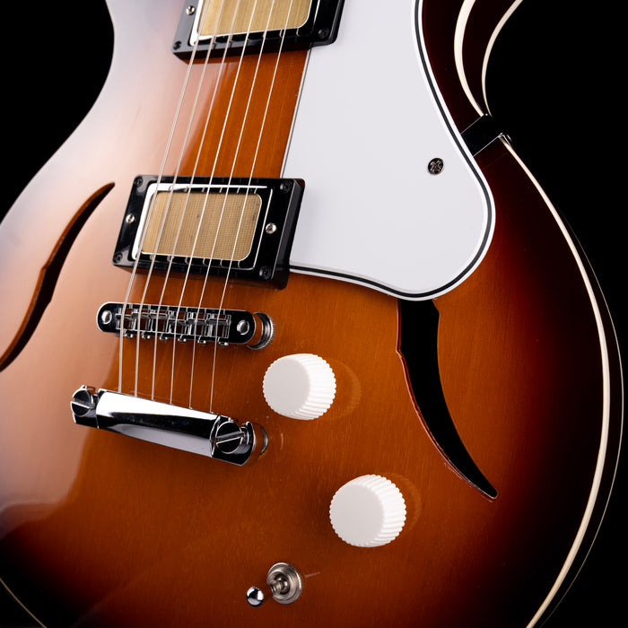 Close-up of a brown electric guitar with a white pickguard