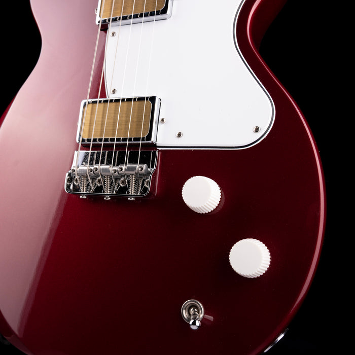 Close-up of a red electric guitar with a white pickguard on a black background