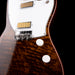 Close-up of a guitar with a focus on the neck and headstock against a black background