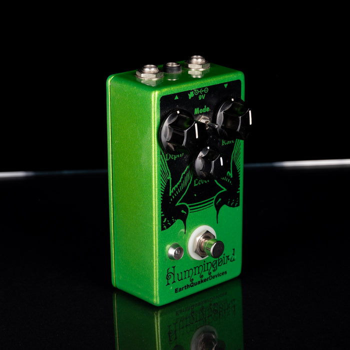 Green guitar effects pedal with black details on a reflective surface