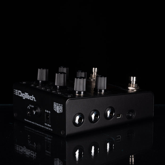 A black DigiTech effects pedal with multiple black and silver knobs, photographed on a glossy black reflective surface against a black background.