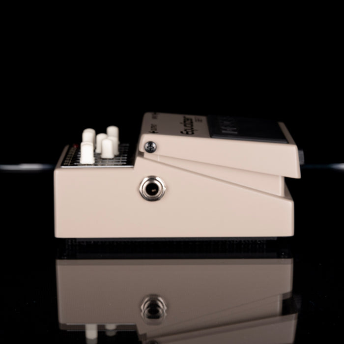 Guitar effects pedal with a cable on a reflective black surface