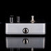 Metallic guitar effects pedal on a reflective black surface with a black background