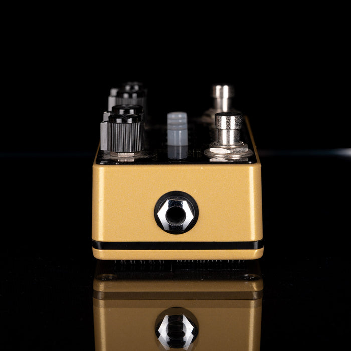 Gold and black electronic device with multiple components on a reflective surface.