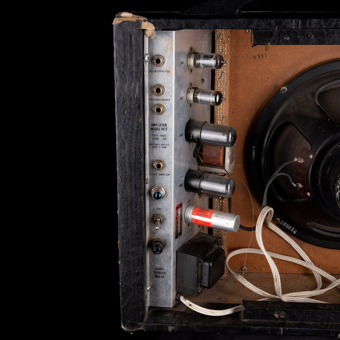 Vintage amplifier with wooden casing and visible wiring on a black background